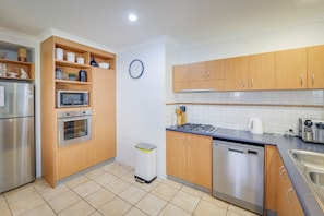 A modern kitchen with wooden cabinets, stainless steel appliances, and a tiled backsplash. - `Dunsborough`s Doorstep` Townhouse Great Location (Dunsborough)