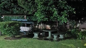 Un jardin avec une table et des chaises, entouré d’un feuillage dense.