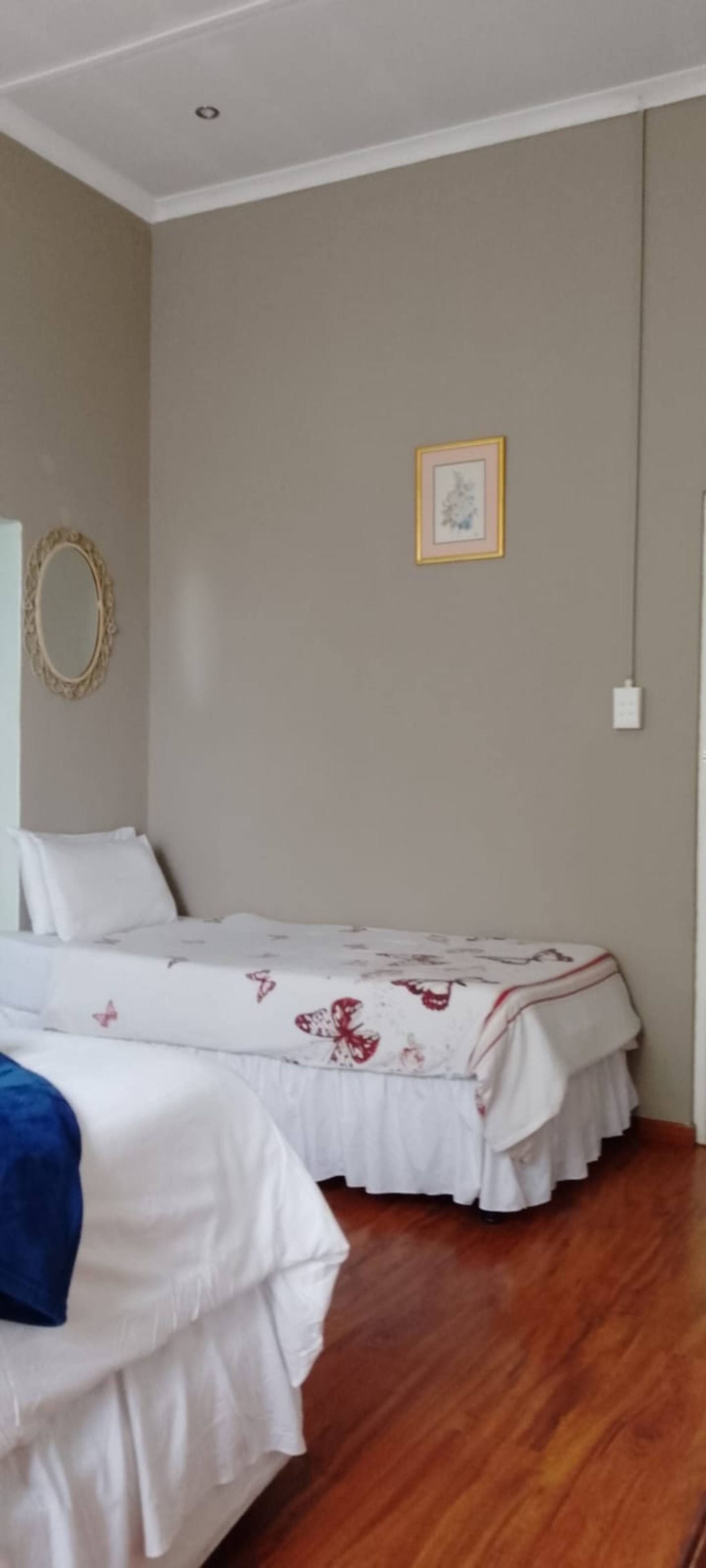 Une chambre avec deux lits, un miroir et un tableau encadré au mur.