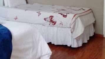Une chambre avec deux lits, un miroir et un tableau encadré au mur.