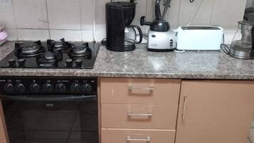 Une cuisine équipée d’une cuisinière à gaz, d’une machine à café, d’un grille-pain et d’une bouilloire.