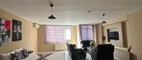 Ein geräumiges Wohnzimmer mit einem großen Bett, einem Sofa, einem Couchtisch und einem Fernseher.