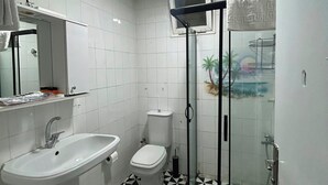 Ein Badezimmer mit weißem Waschbecken, WC und Duschkabine.