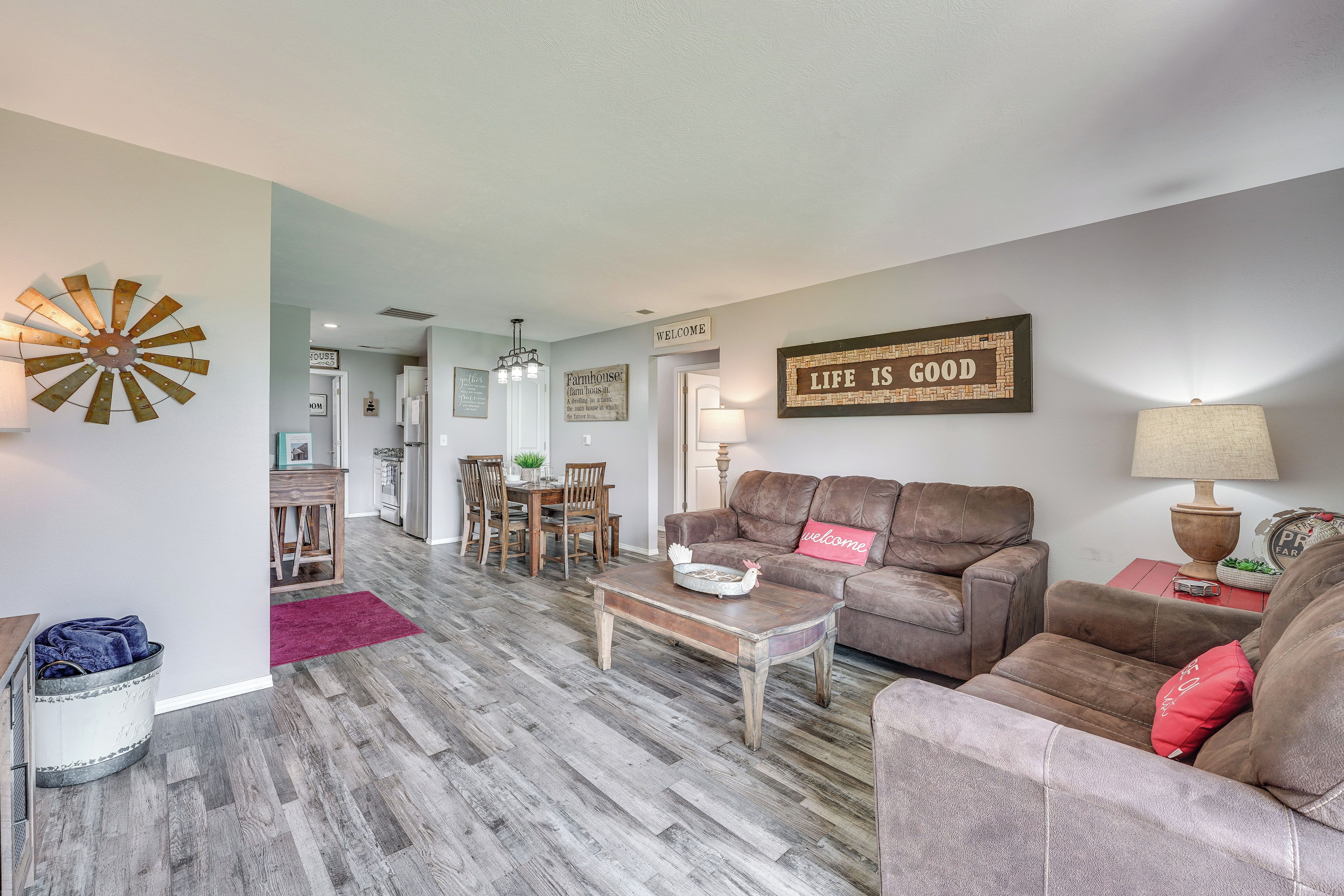A living room with a brown leather sofa, a wooden coffee table, and a dining area with a wooden table and chairs.