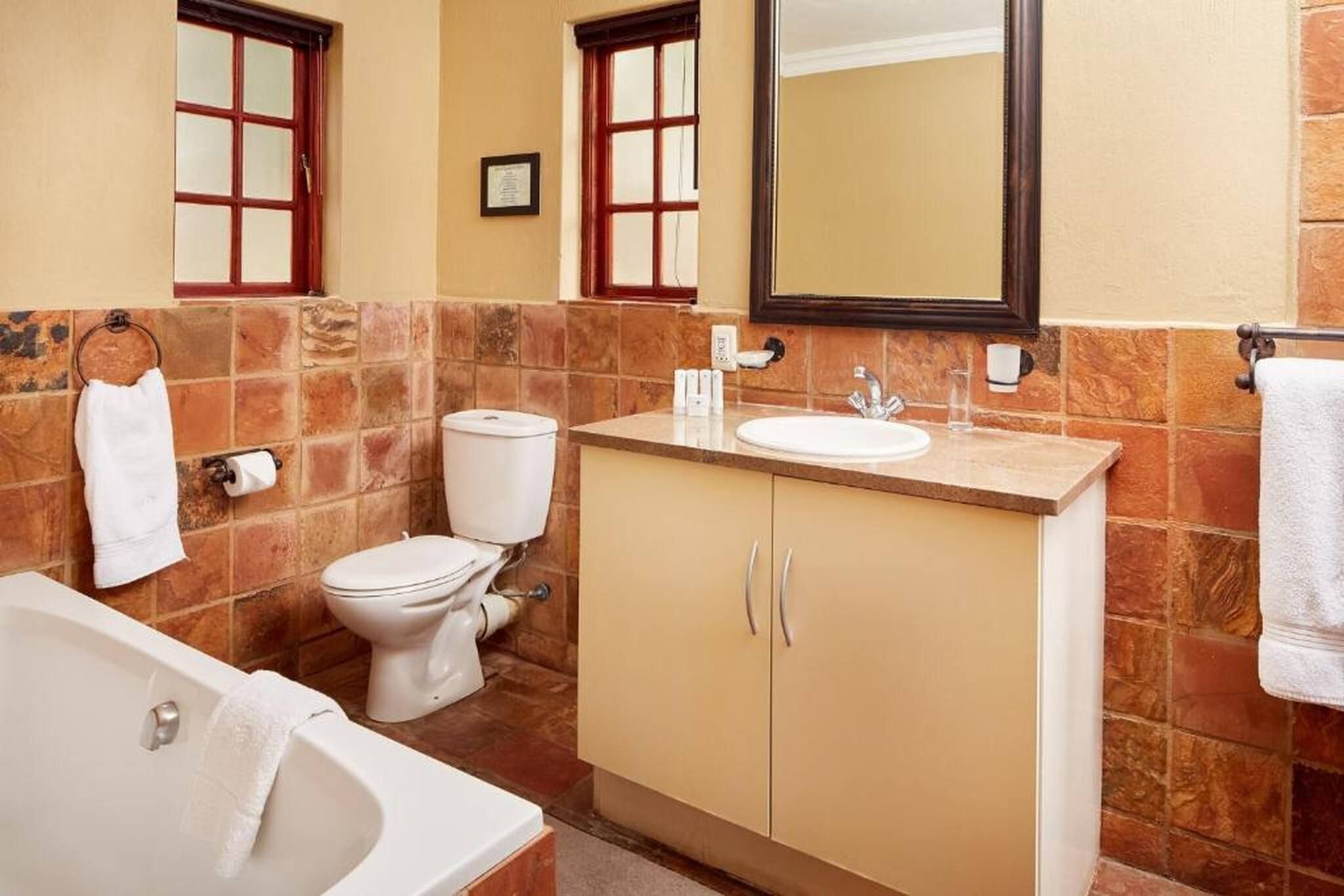 A bathroom with a bathtub, toilet, sink, and mirror.