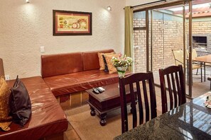 Una sala de estar con un sofá de cuero marrón, una mesa de centro y una mesa de comedor con sillas.
