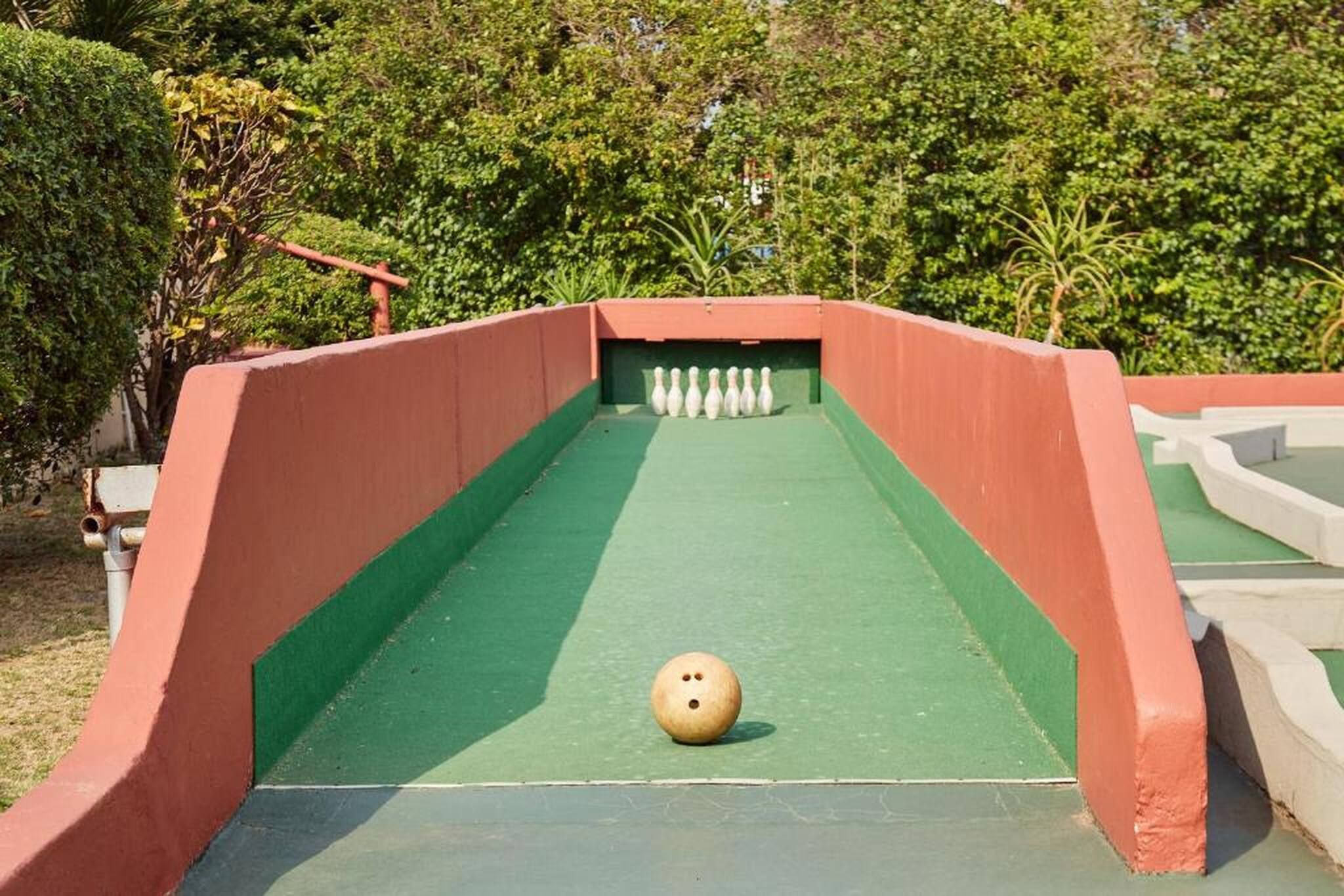 A bowling alley with a green lane and a single bowling ball at the start.