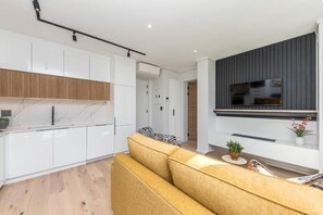 A modern kitchen with white cabinets, a marble countertop, and a built-in oven. - Luxury One-Bedroom with Balcony -Unit 9 (Stellenbosch)