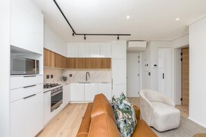 Una cocina moderna con armarios blancos, una pared decorativa de madera y un microondas integrado.