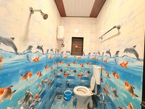 A bathroom with a dolphin and fish mural, a toilet, and a shower.