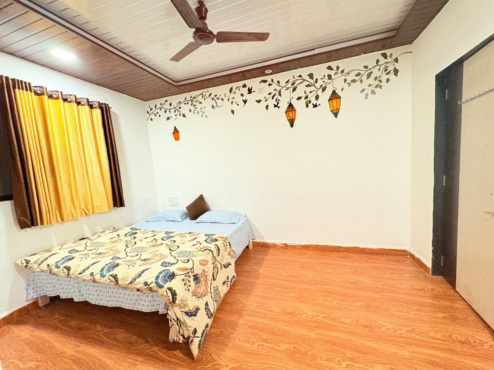 Un dormitorio con cama, ventilador de techo, ventana con cortinas y pared con detalles decorativos.