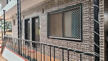 Un edificio con fachada de ladrillo, cerca metálica y un ventanal con mosquitero.