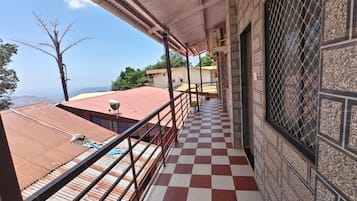 A balcony with a checkered floor, metal railing, and a view of the landscape.