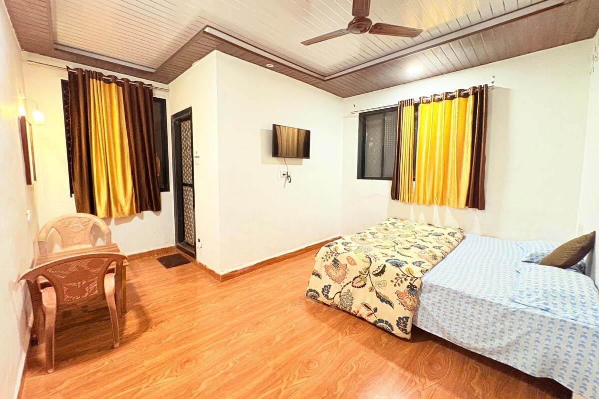A room with a bed, a chair, a ceiling fan, and curtains.