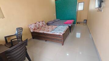 A room with a bed, a chair, a television, and a green partition wall.