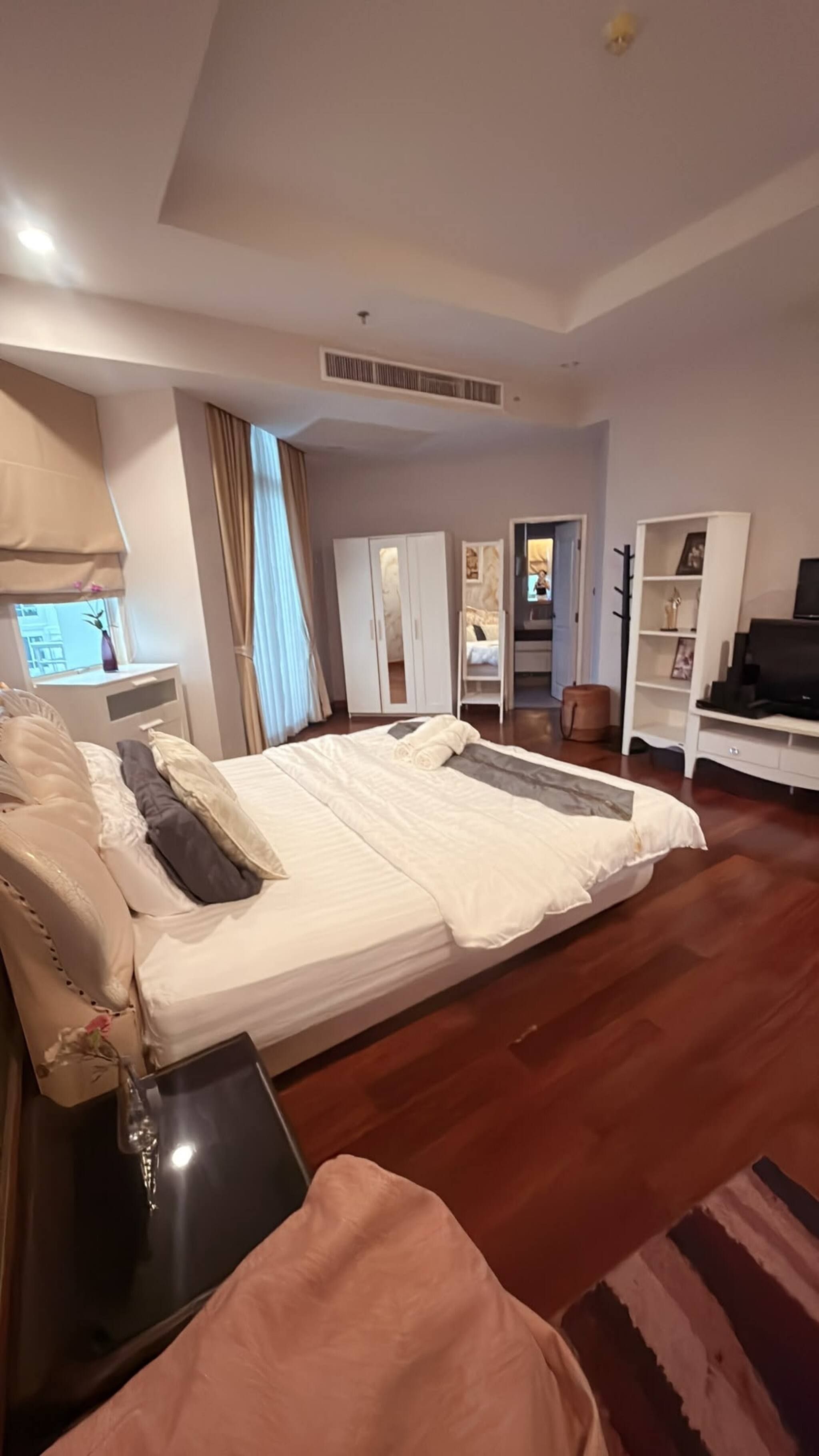 Quarto espaçoso com uma cama grande, mesa de cabeceira, guarda-roupa e televisão.