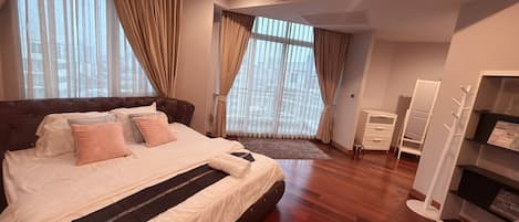 Un dormitorio con una cama grande, cortinas, un armario y un espejo.
