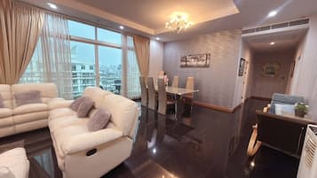 A modern living room with a sofa, dining area, and a view of the cityscape.