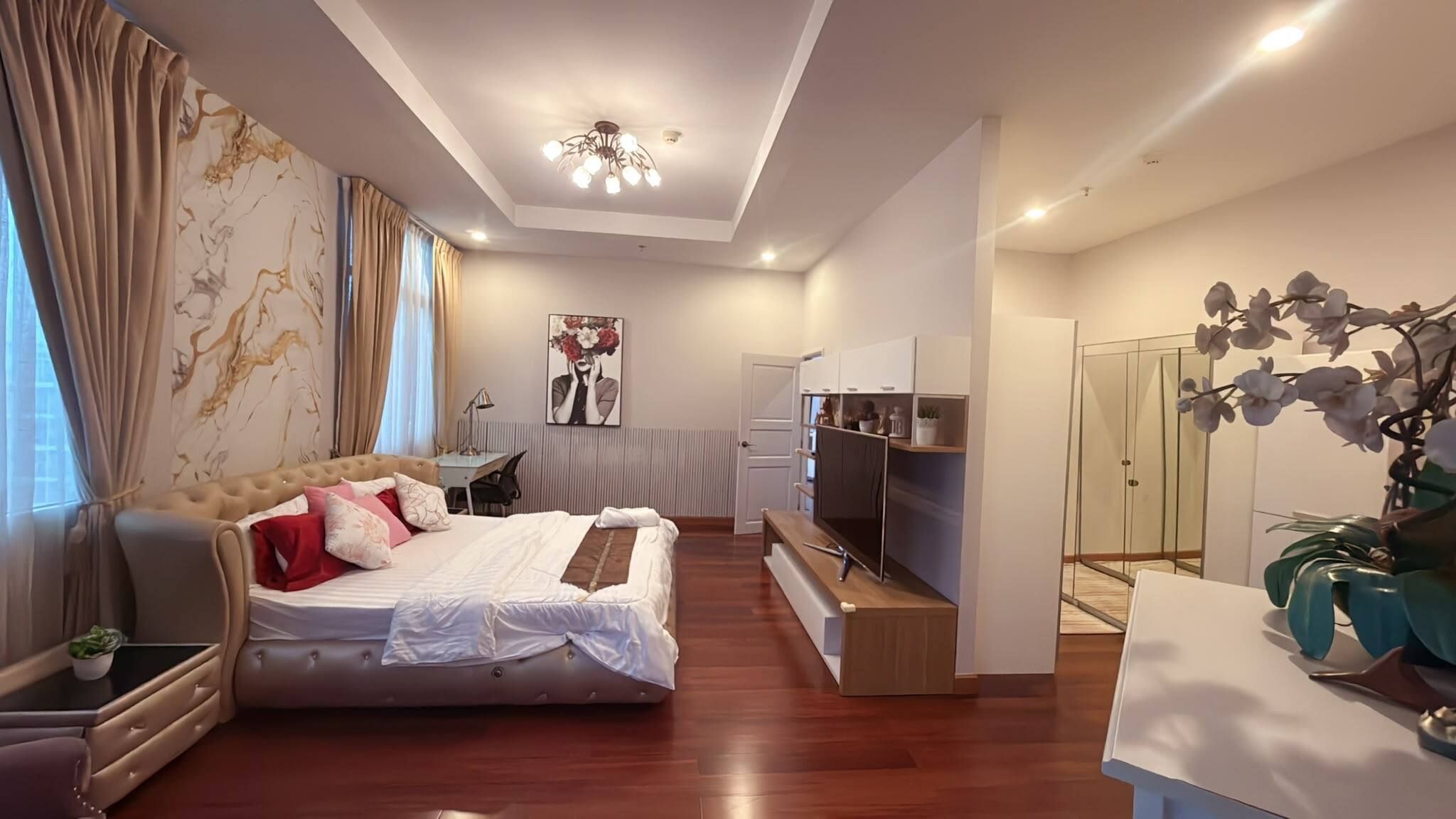 A modern bedroom with a bed, a desk, a TV, and a wardrobe.