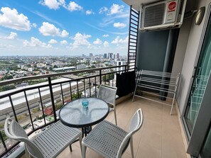 Un balcone con tavolo e sedie, uno stendibiancheria e vista sulla città.