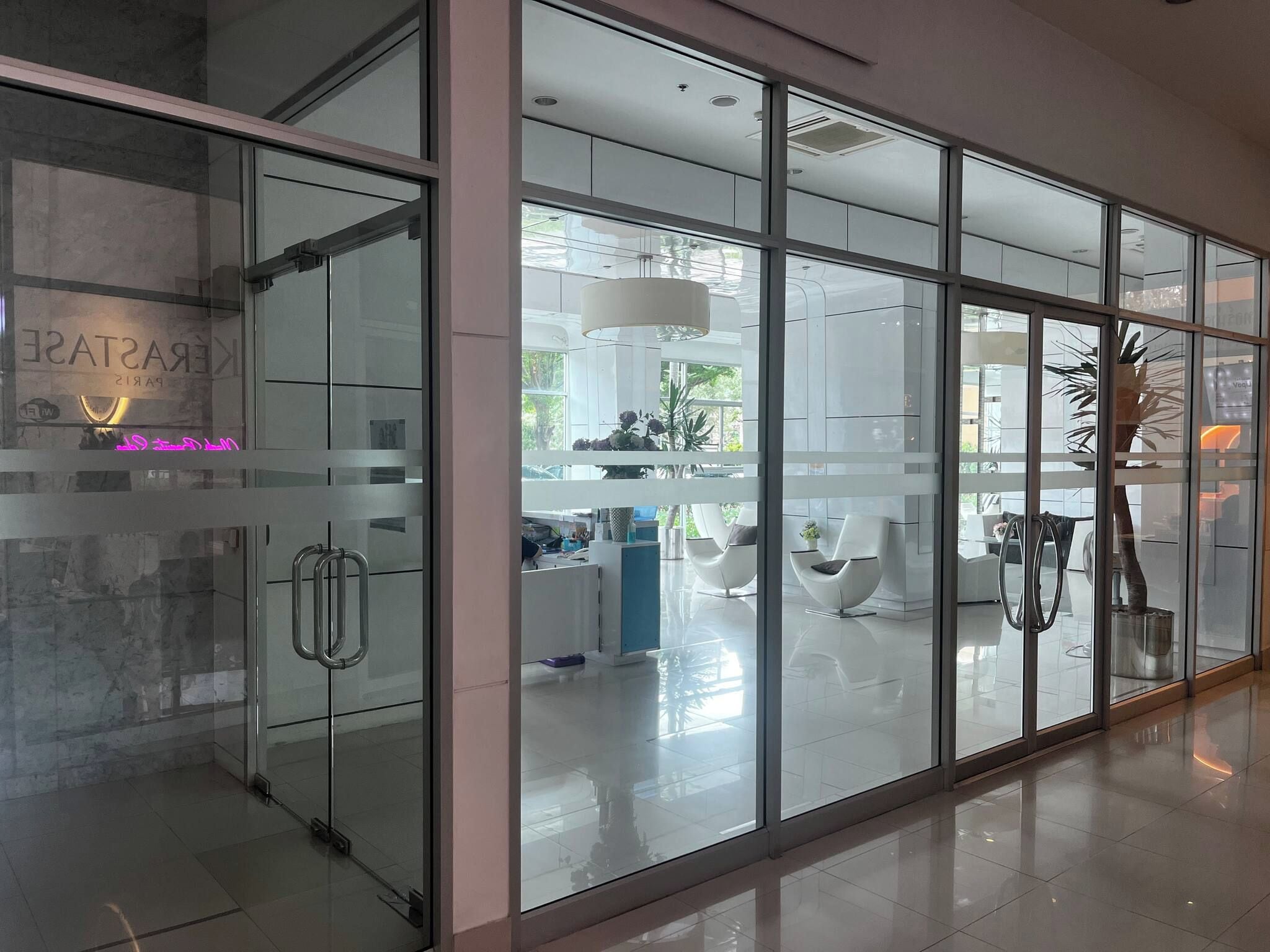 A modern interior with glass partitions, a reception desk, and contemporary furniture.
