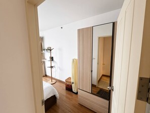 Una camera da letto con uno specchio grande, un letto, un armadio e un espositore per piante.