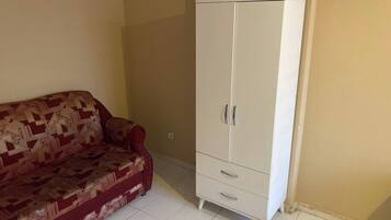 A room with a patterned sofa and a white wardrobe.