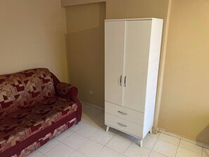 Una habitación con un sofá estampado y un armario blanco.