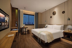 A hotel room with a large bed, a desk, a chair, a small table, and a window with a city view. - Pinman Yun Hotel (changsha)
