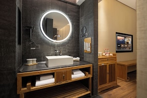 A modern bathroom with a round mirror, a rectangular sink, wooden cabinets, and a wooden vanity. - Pinman Yun Hotel (changsha)