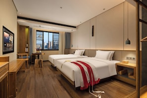 A hotel room with two beds, a wooden desk, a small table with a vase, and a city view through the window. - Pinman Yun Hotel (changsha)