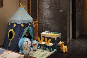 Zona de jocs infantil amb una tenda, joguines de peluix i una taula amb blocs de construcció.