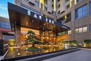 A modern hotel entrance with a reflective pool, a well-maintained garden, and a clear view of the building's facade. - Pinman Yun Hotel (changsha)