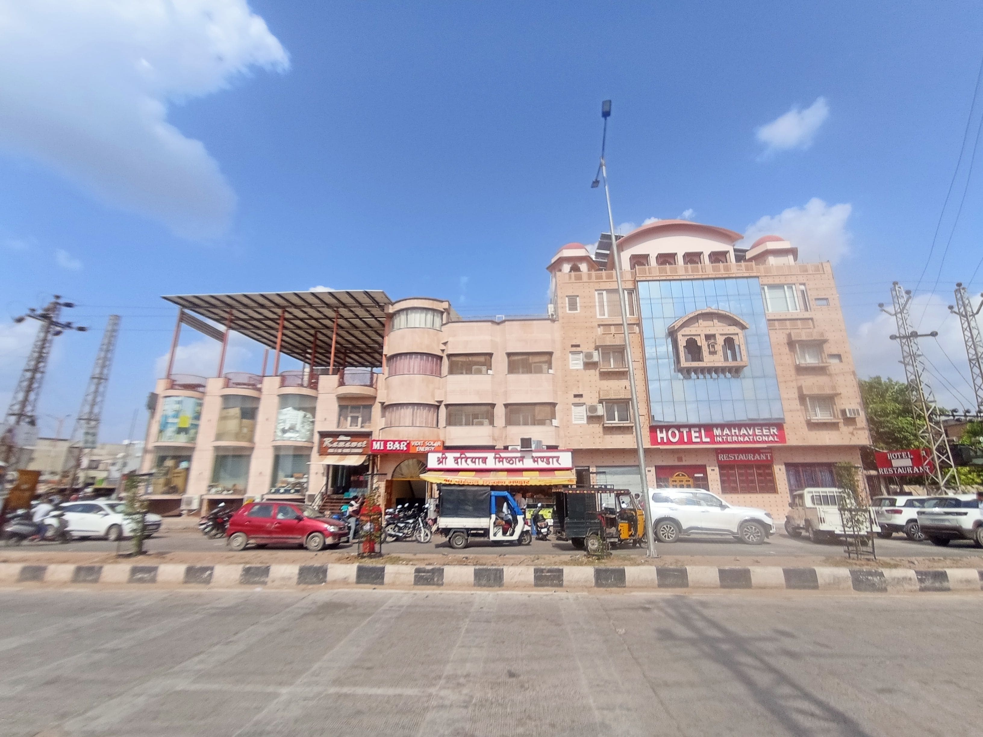A multi-story hotel with a prominent sign for 'Hotel Mahaveer International' and a visible restaurant on the ground floor.