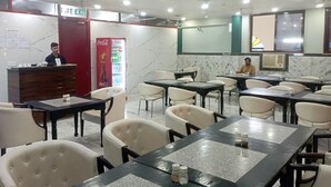 Restaurante com mesas e cadeiras, geladeira Coca-Cola e placa de saída de incêndio.