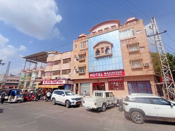 A multi-story building with a prominent sign for 'Hotel Mahaveer International' and a restaurant.
