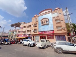 Un edificio de varios pisos con un letrero llamativo del 'Hotel Mahaveer International' y un restaurante.