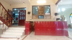 Um saguão de hotel com escada, balcão de recepção e uma estátua de Buda.