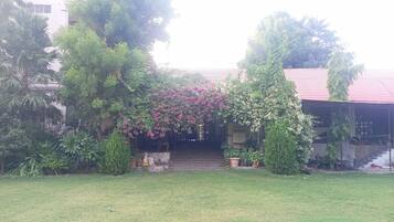 Un edificio con techo rojo, rodeado de abundante vegetación y un césped cuidado.