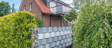A modern house with a sloped roof, a brick exterior, and a metal fence.