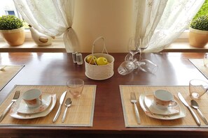 A dining table set for two with placemats, cutlery, a fruit basket, and wine glasses. - "BERNSTEIN" with balcony / sea view (Sassnitz)