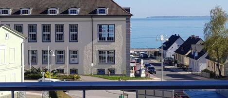 A residential building with a tiled roof, multiple windows, and a view of the sea.