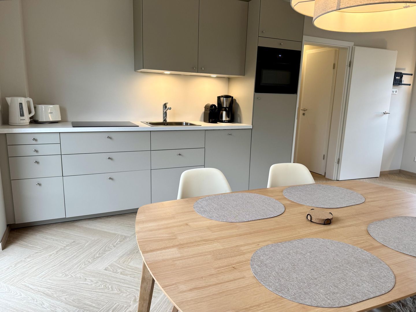Et moderne køkken med vask, skabe og et spiseområde med bord og stole.