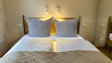 A double bed with striped bedding and a quilted cover.
