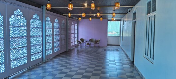 A corridor with patterned windows, checkered floor, and hanging lights.