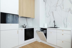 A modern kitchen with white cabinetry, a wooden upper cabinet, a black dishwasher, and a marble backsplash. - Szczecin | 21 Mała Odrzańska | Cosy Apartment | Air conditioning (Szczecin)