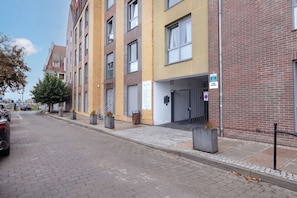 A multi-story residential building with a brick facade, a gated entrance, and a parking area with cars. - Szczecin | 21 Mała Odrzańska | Cosy Apartment | Air conditioning (Szczecin)