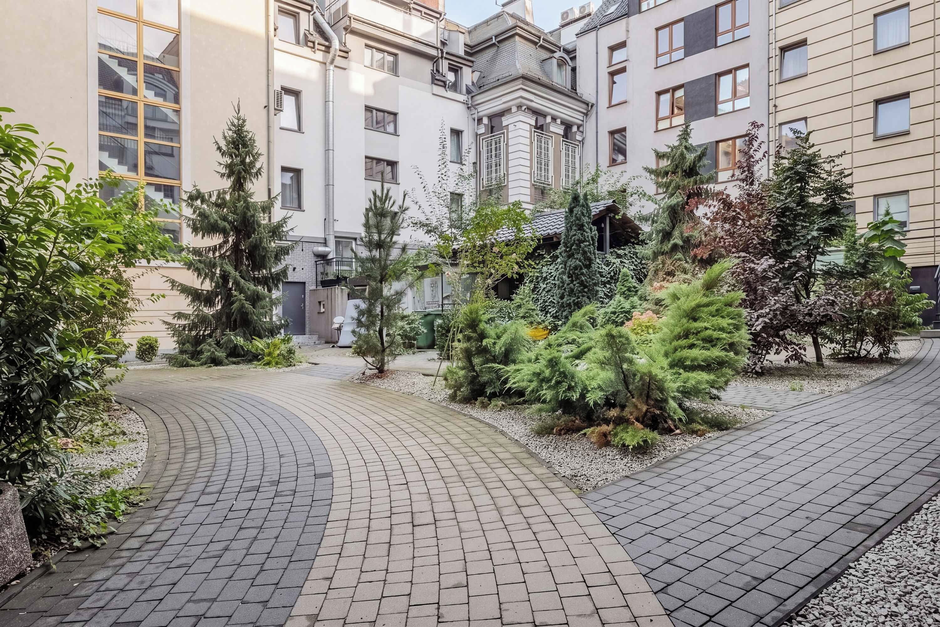 A courtyard with a paved walkway, surrounded by buildings with large windows and balconies.