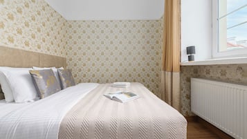 Un lit bien fait, avec une couvre-lit à motifs, un oreiller orné de motifs floraux et un magazine posé sur le lit.