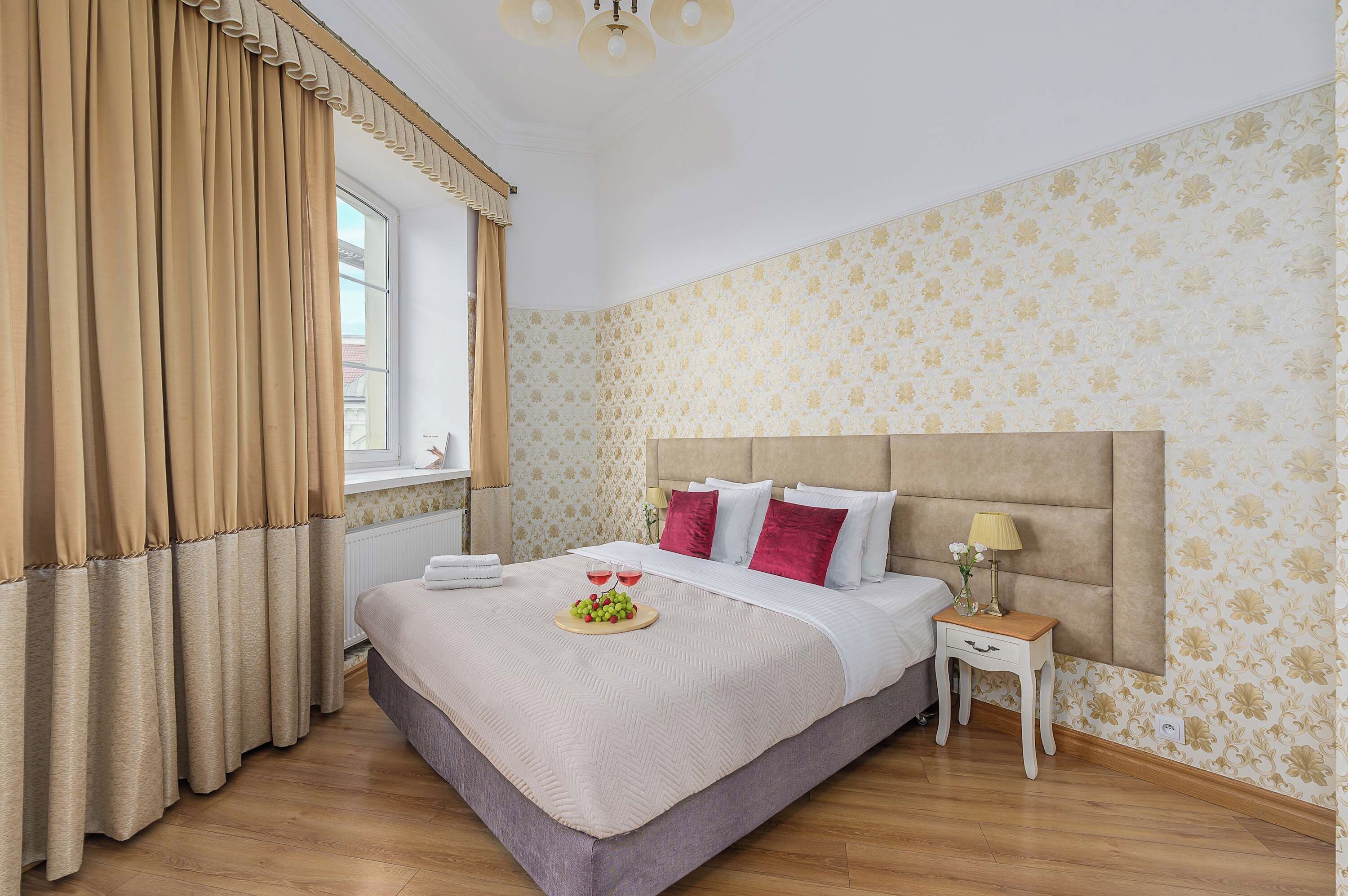 A hotel room with a large bed, a bedside table, and a window with curtains.